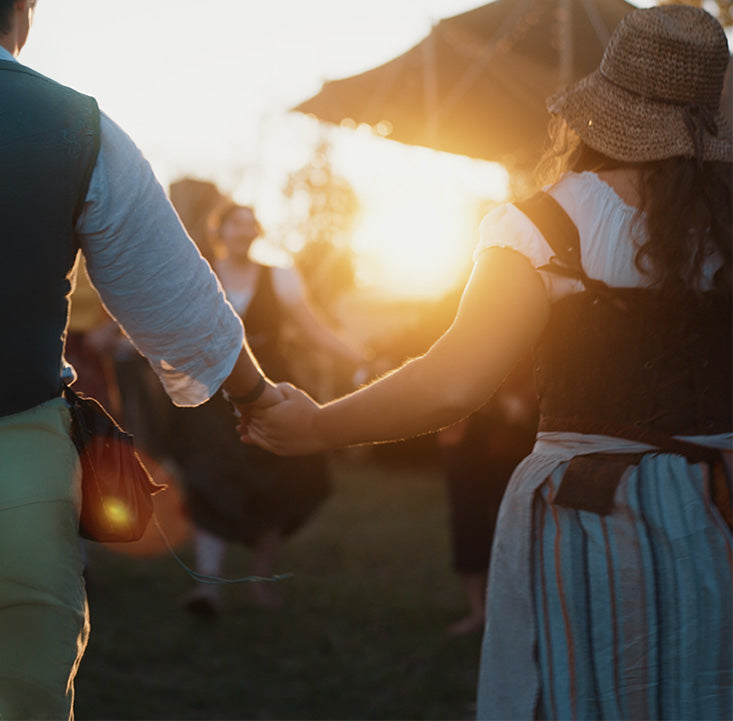 Two people holding hands with a warm glow from the sun in the background